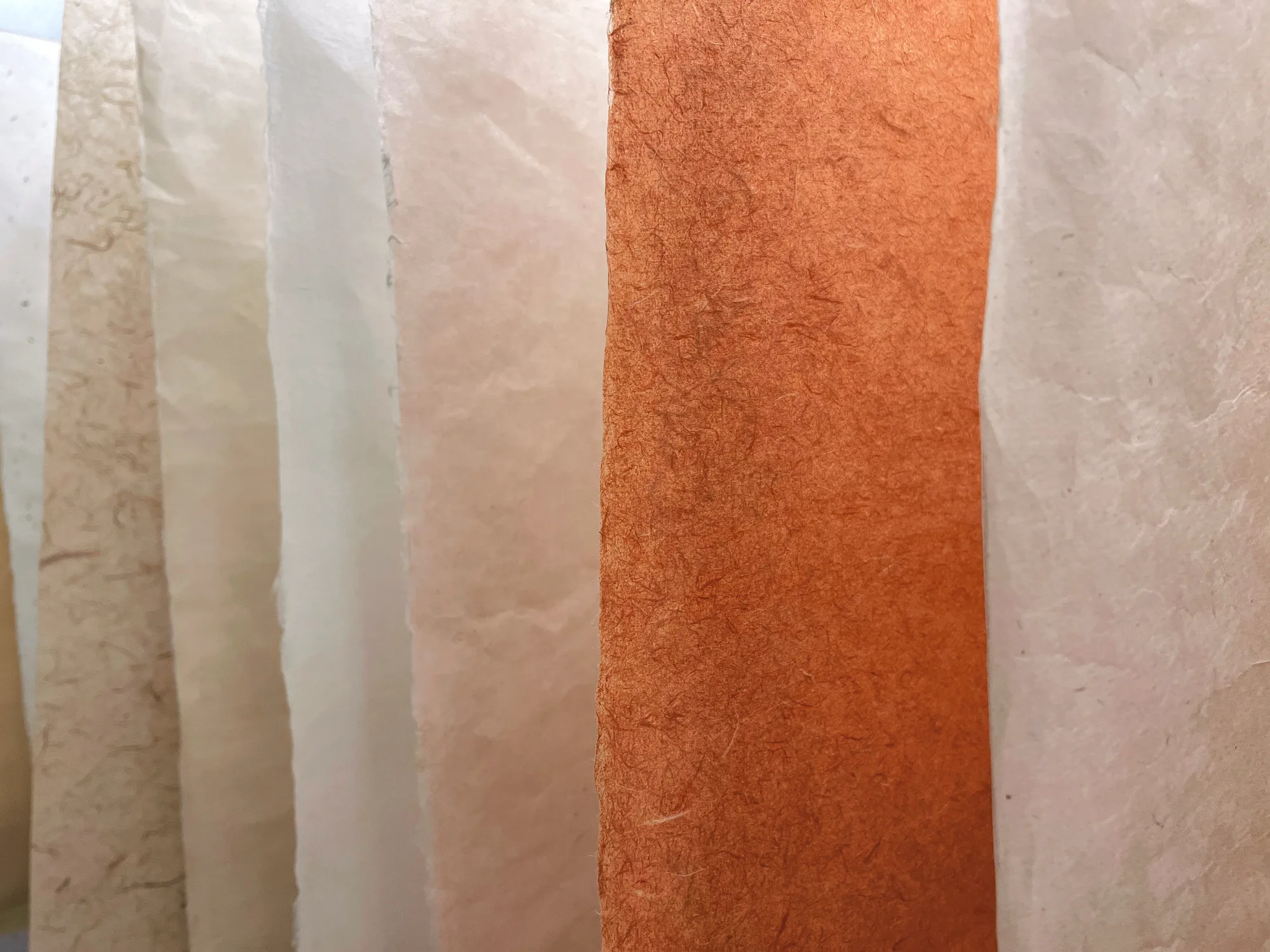 Layered sheets of handmade hanji paper, in warm cream and burnt orange tones